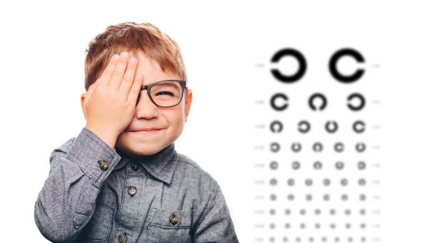boy having eye exam with eye chart and covering one eye. Miopía infantil